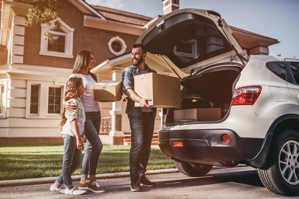 family carrying boxes next to a car.