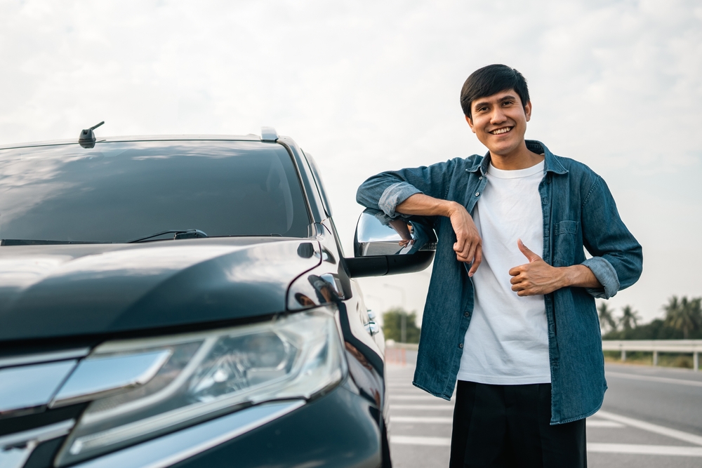 man smiling next to his new car.