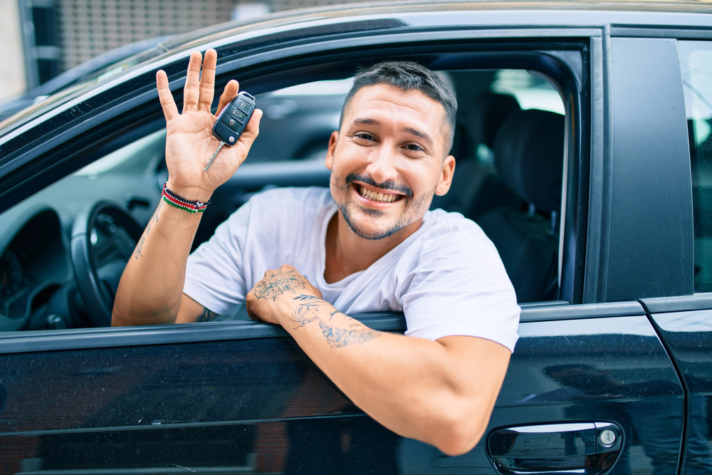 man inside his new car showing the key.