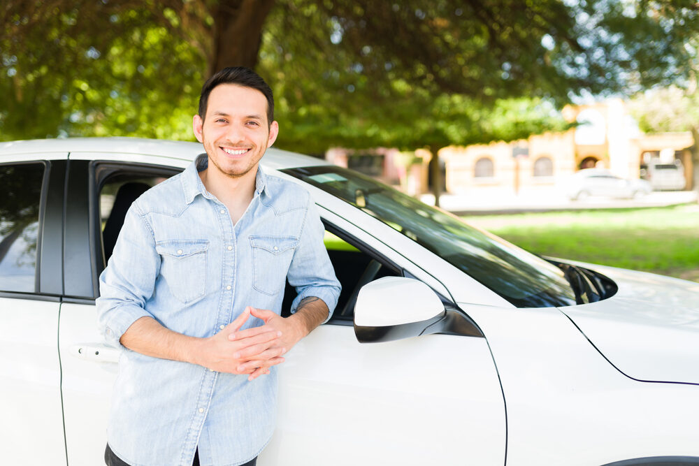 man smiling next to his new car.