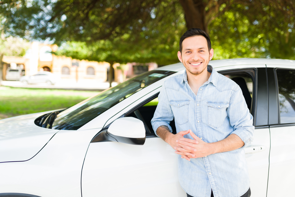 man smiling next to his new car.